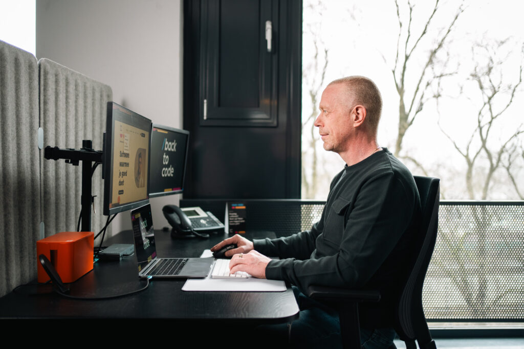 Medewerker Back to code zit aan zijn bureau te werken.